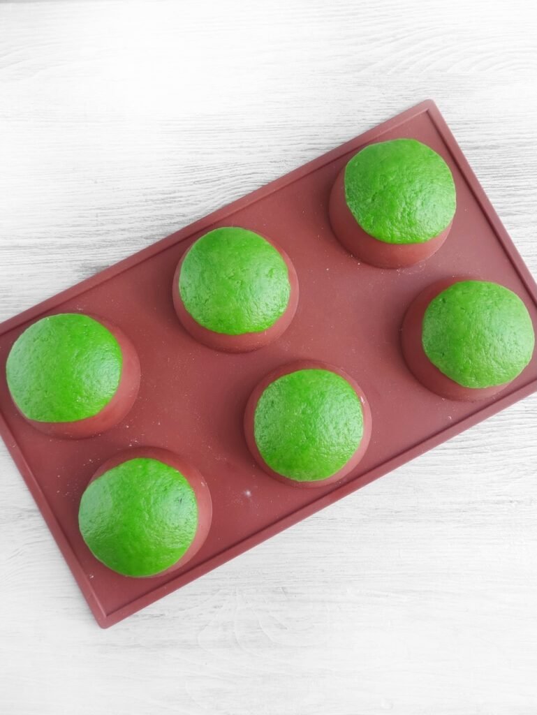 Step 2: Shaped green cookie dough placed over a silicone mold to form cups for candy-filled homemade party treats.