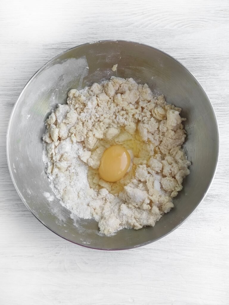 Step 1: Mixing flour, sugar, butter, and egg in a bowl to make dough for candy-filled Halloween witch cookies.