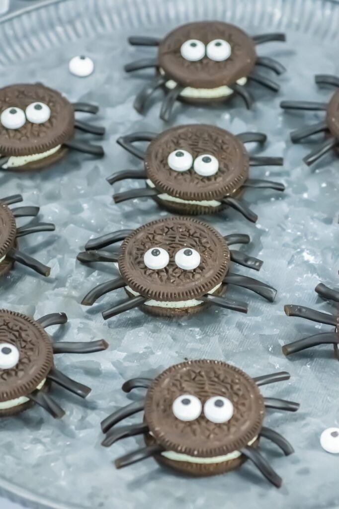 Close-up of Oreo Spider Cookies with candy eyes and black licorice legs arranged on a serving tray, a cute and easy no-bake Halloween dessert for kids and parties.