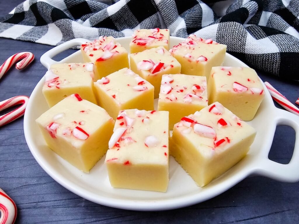 Macro shot of peppermint fudge highlighting creamy white chocolate and crushed candy cane pieces.