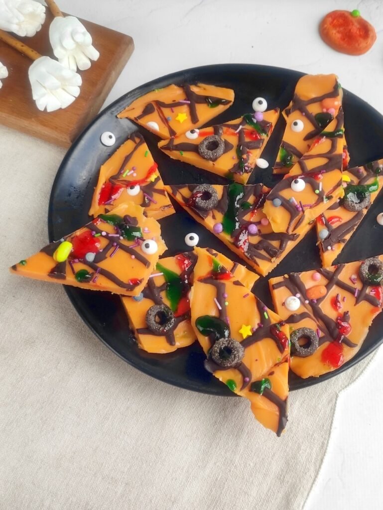dessert displayed on a plate with orange shards decorated with edible eyes, candy, and spooky toppings for parties.