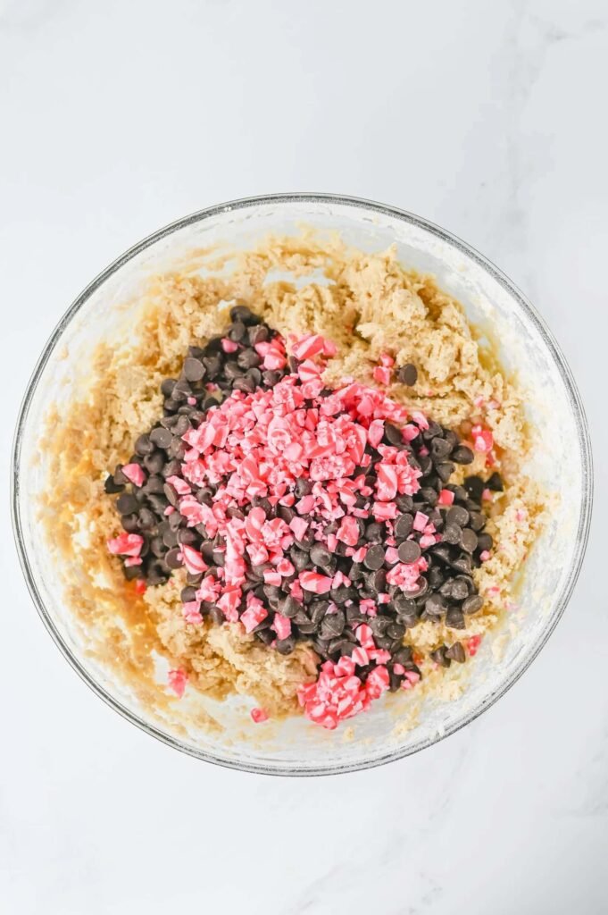 Chocolate chips and crushed peppermint candies added to cookie dough for peppermint chocolate chip cookies.