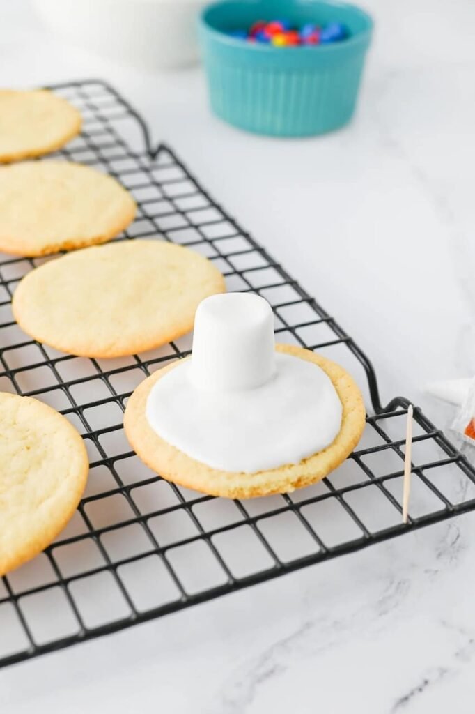 Desserts topped with white icing and a marshmallow head, showing the first step in decorating.
