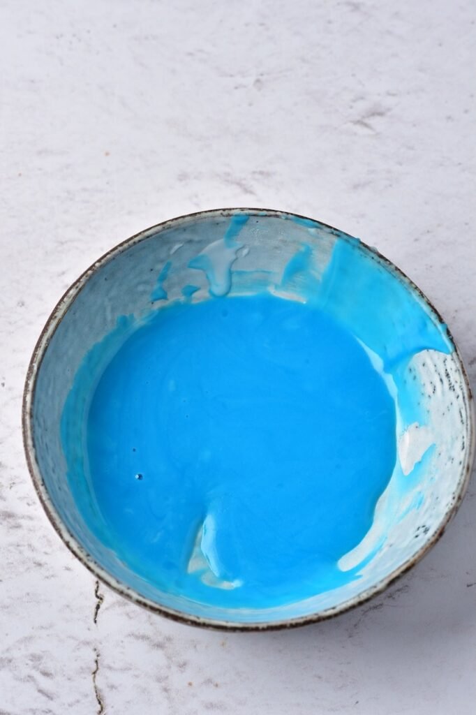 Bowl of bright blue cookie icing ready for decorating.