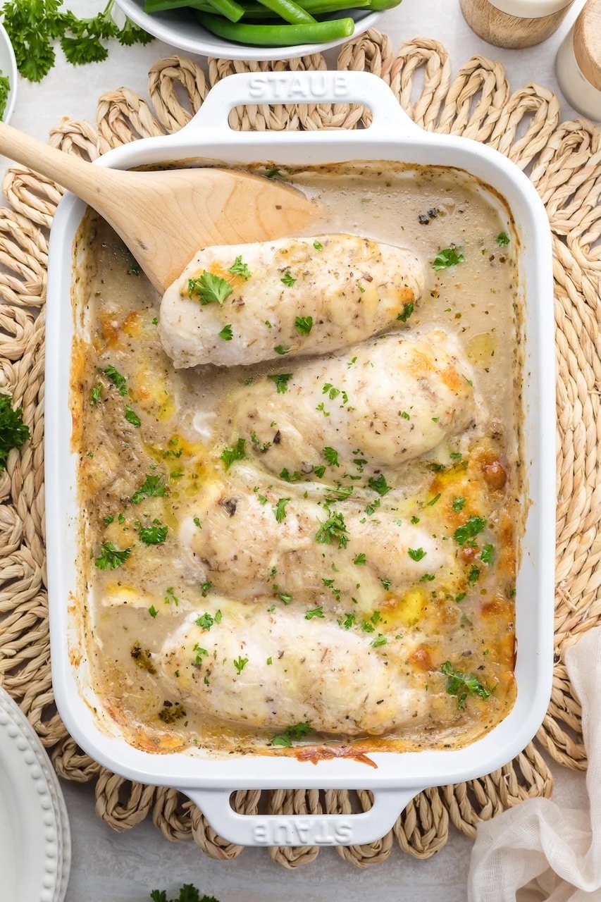 Baked chicken Florentine casserole with creamy mushroom sauce and parsley in a white Staub baking dish