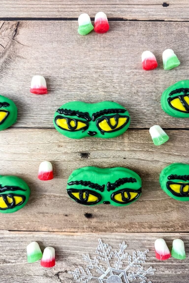 Grinch eye Nutter Butter cookies decorated with green candy coating and yellow eyes outlined in black icing, festive Christmas treat