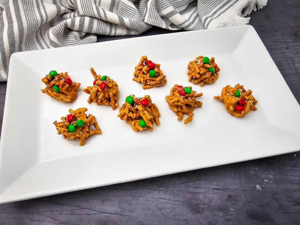 festive no-bake Christmas haystack cookies made with chow mein noodles, butterscotch, and red and green sprinkles on a holiday plate.