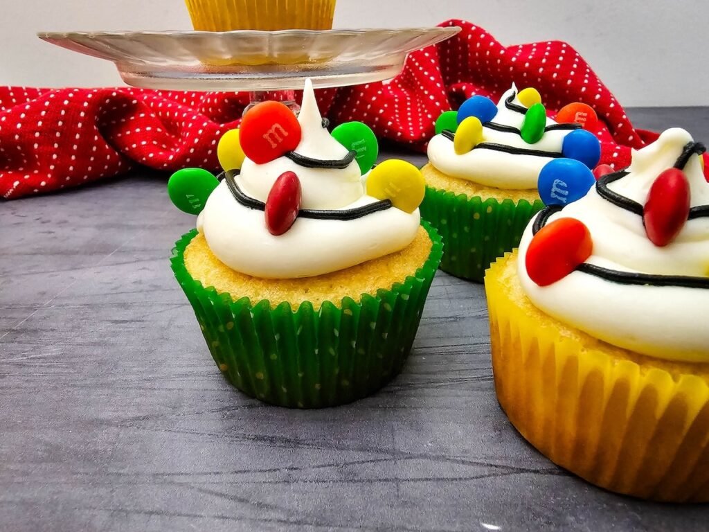 Side view of with buttercream frosting, black icing, and colorful M&M candies arranged like festive holiday lights.