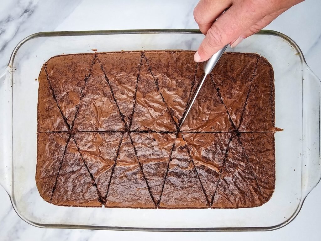 Hand cutting baked brownies into triangles for christmas Santa Hat Brownies.