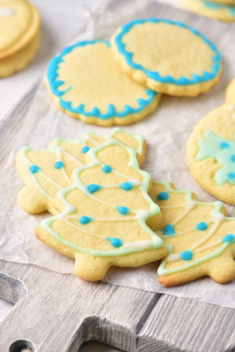 Christmas sugar cookies decorated with blue and green icing in tree and round shapes on parchment paper