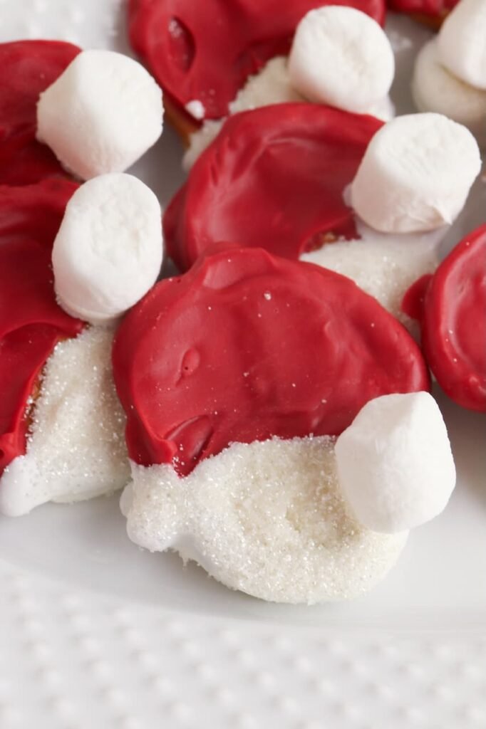 Close-up of red and white Pretzel Santa Hats made with chocolate, sugar sprinkles, and mini marshmallows showing detail of the festive texture.