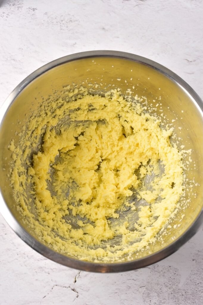 Creamed butter and sugar mixture in a stainless steel mixing bowl.