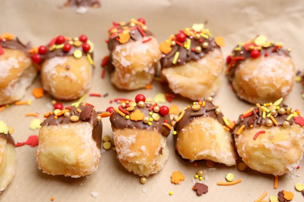 Dessert on parchment paper decorated with melted chocolate and colorful fall sprinkles during step two.