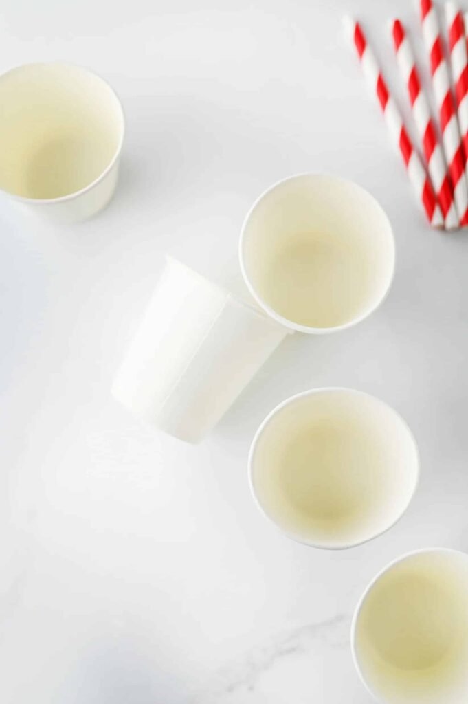 Step 1 — small paper cups arranged on a white surface with red striped straws ready for use.