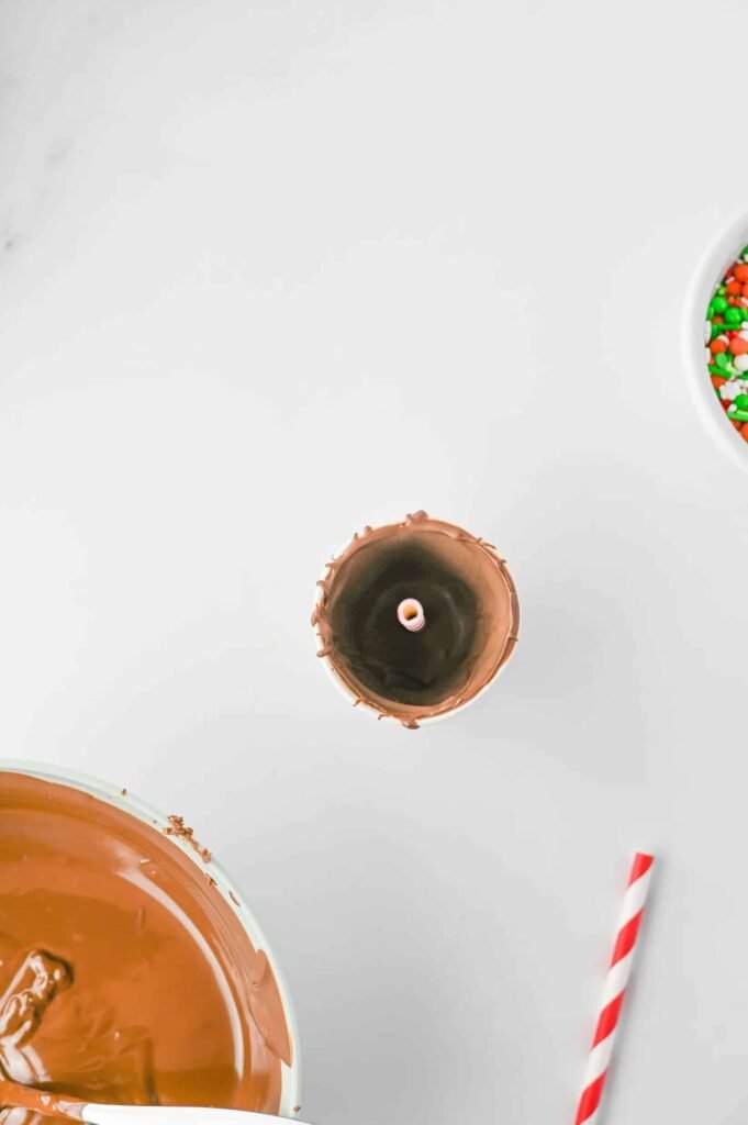 Step 3 — coated paper cup filled with melted chocolate and red striped straw inserted in the center.