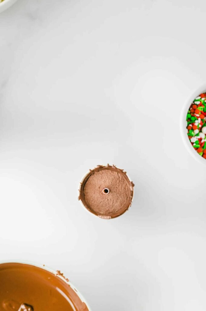 Step 4 of homemade hot chocolate sticks recipe — paper cup filled with cocoa mix and chocolate layer, ready to be sealed and decorated.