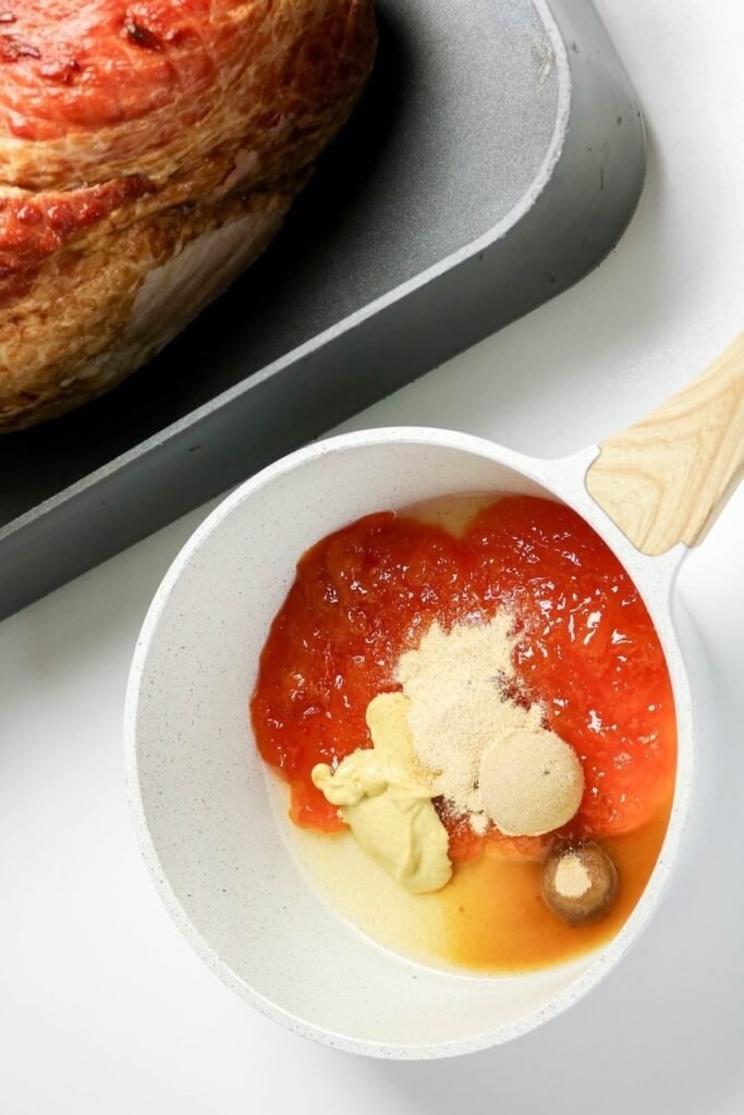 Apricot preserves, Dijon mustard, brown sugar, apple cider vinegar, and garlic powder in a saucepan ready to be heated into a sweet and tangy glaze.