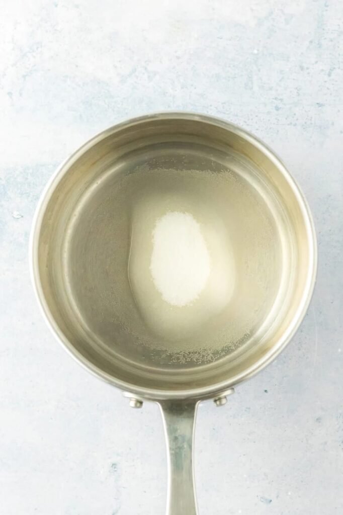 Step 1 — sugar dissolving in water in a stainless steel saucepan.