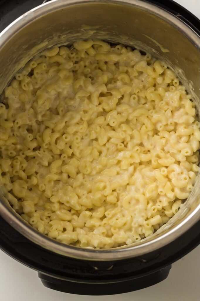 Creamy homemade pasta inside an Instant Pot after mixing in melted cheese and milk.