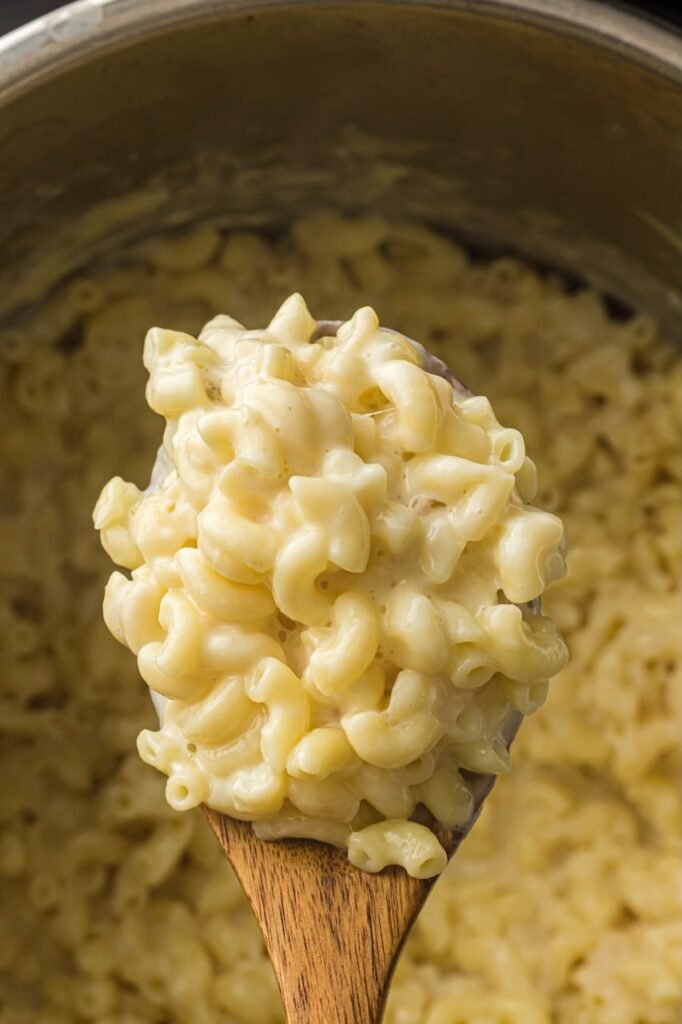 A wooden spoon lifting a scoop of creamy homemade mac and cheese straight from the Instant Pot.