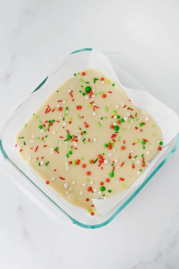 Holiday dessert topped with red, green, and white sprinkles before chilling in the refrigerator.