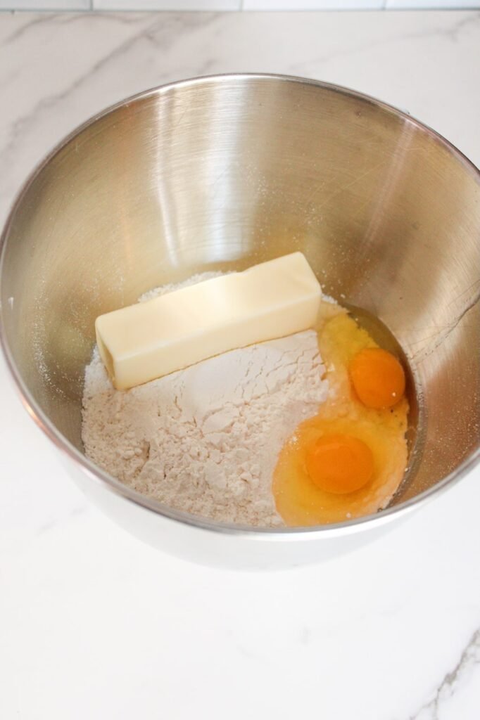 Butter, eggs, and cake mix in a metal mixing bowl, ready to make festive green holiday cookies.