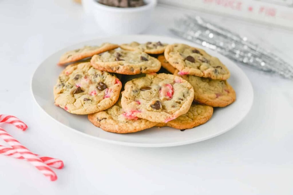 Freshly baked peppermint chocolate chip cookies with crushed candy canes on a white plate, ready to serve.