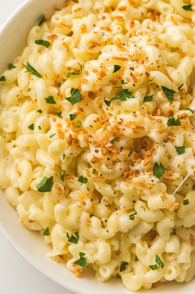 Bowl of creamy Instant Pot mac and cheese topped with golden breadcrumbs and fresh parsley.