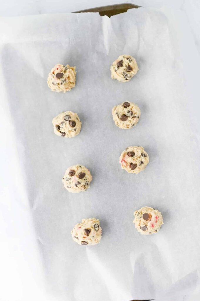 Scooped dough balls on a parchment-lined baking sheet ready to chill or bake.
