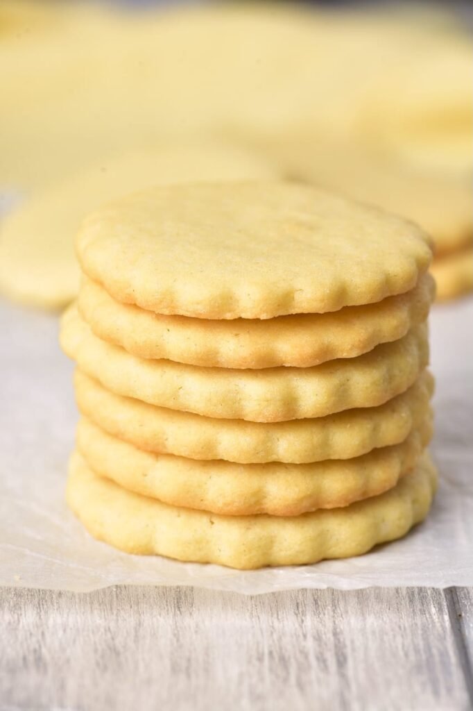 Stack of soft, buttery Christmas sugar cookies on parchment paper ready for decorating or gifting.