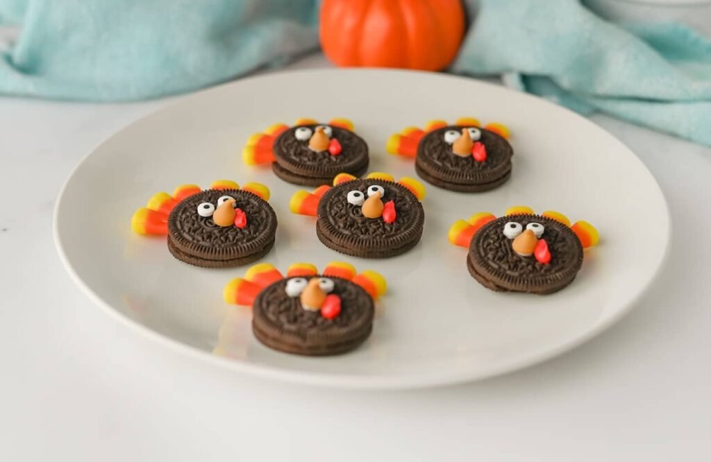Plate of Turkey Oreo Cookies decorated with candy corn feathers, candy eyes, and red frosting wattles, served as a fun no-bake Thanksgiving dessert.