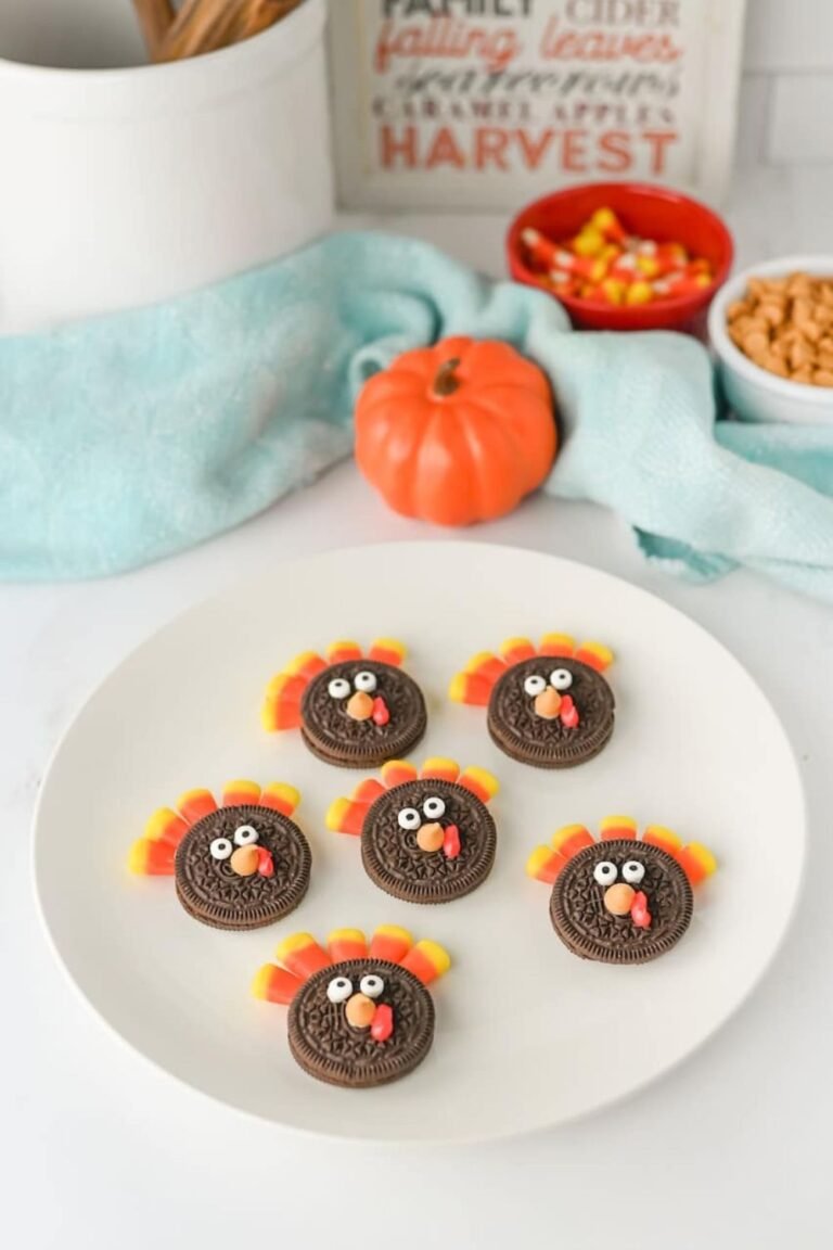 Plate of Turkey Oreo Cookies decorated with candy corn feathers and candy eyes, styled with a pumpkin and fall-themed decor in the background.