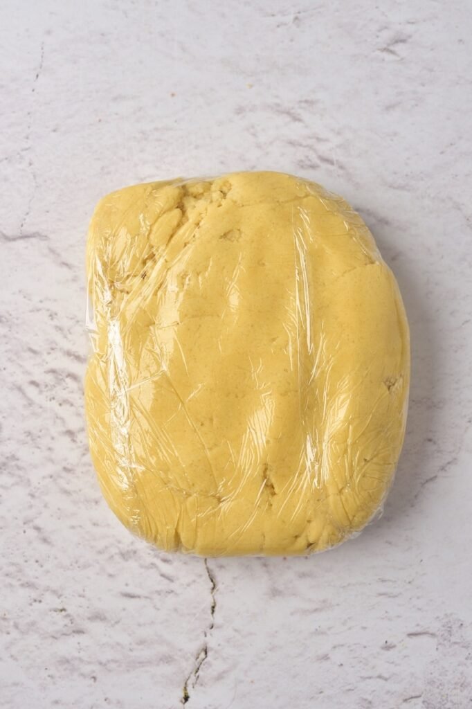Wrapped sugar cookie dough in plastic wrap ready to chill before rolling and cutting Christmas cookies.