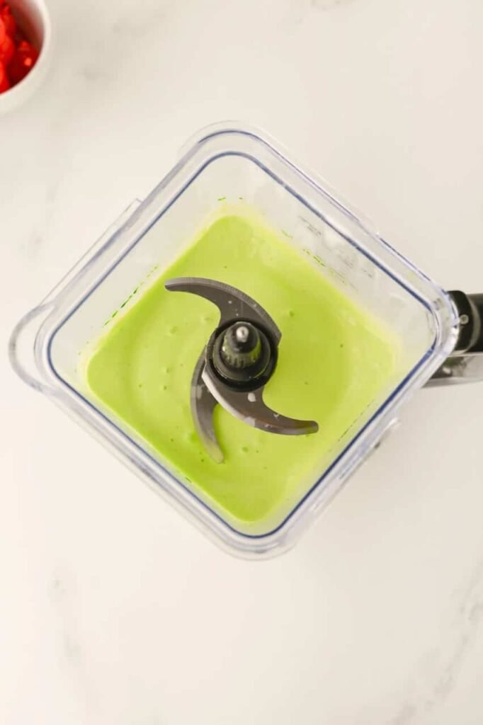 Bright green Grinch milkshake mixture being blended in a high-speed blender until smooth and creamy.