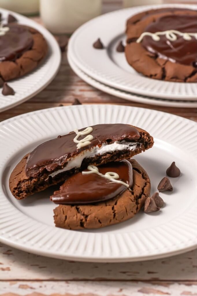 Crumbl chocolate mallow cupcake cookies cut open showing marshmallow filling and chocolate ganache topping on a plate.