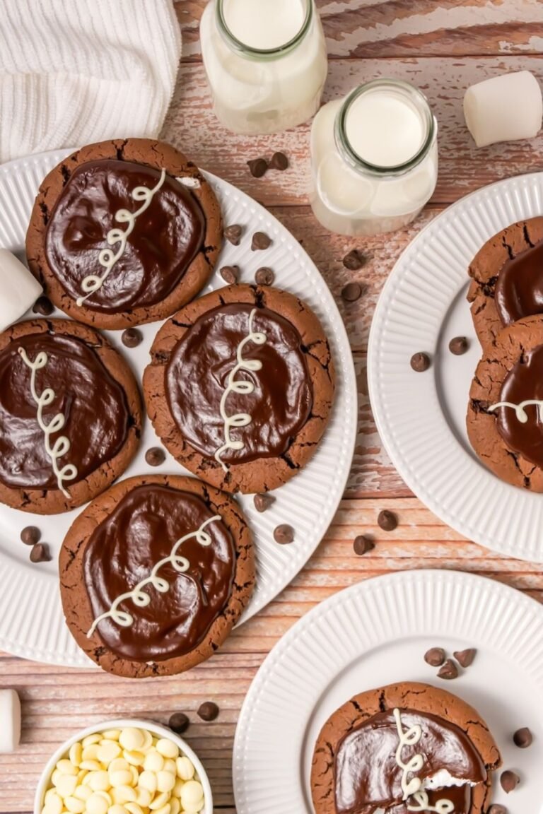 Plate of Crumbl chocolate mallow cupcake cookies topped with chocolate ganache and white chocolate drizzle served with milk and marshmallows.
