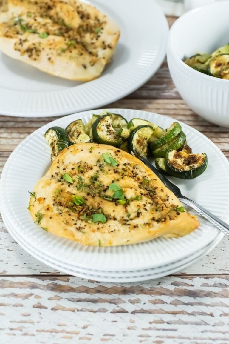 juicy broiled chicken breast served with roasted zucchini and fresh herbs on a white plate — an easy, healthy dinner recipe.