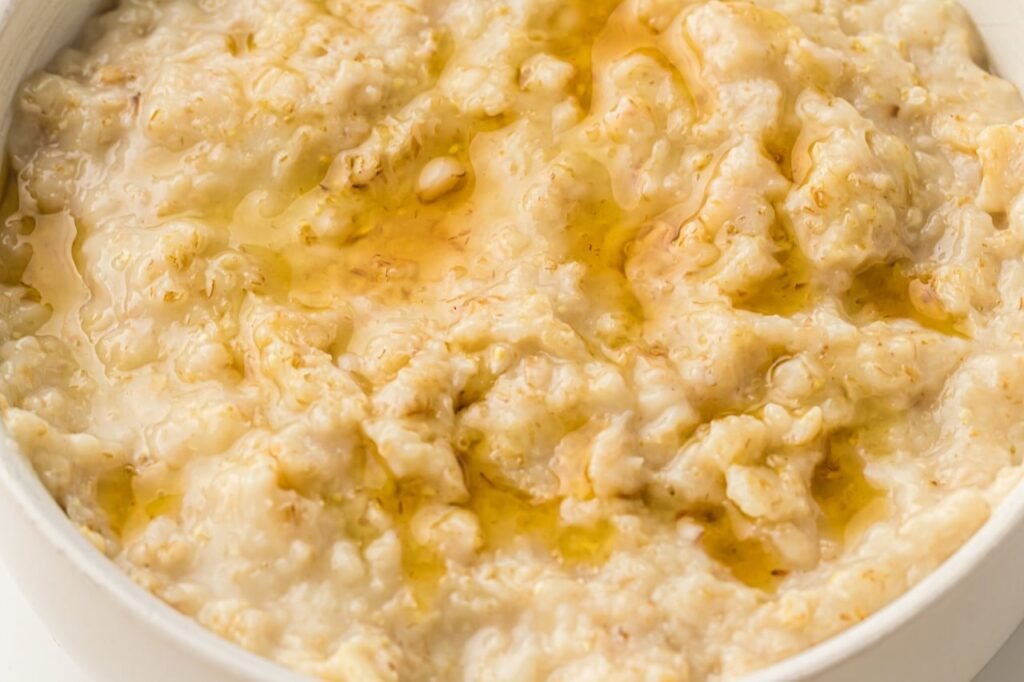 Close-up view of creamy cooked oatmeal in a bowl with a light drizzle on top, showing the thick, smooth texture of Instant Pot oatmeal after cooking.