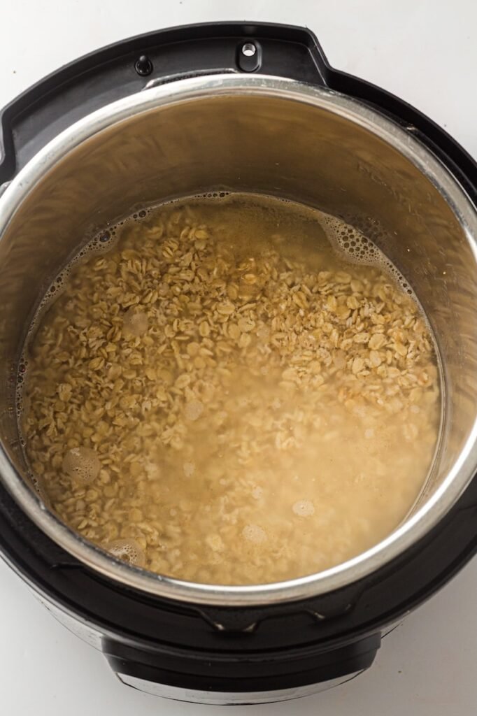 Rolled oats and water mixed together inside the stainless steel, showing the first step of preparing oatmeal before the lid is sealed and pressure cooking begins.