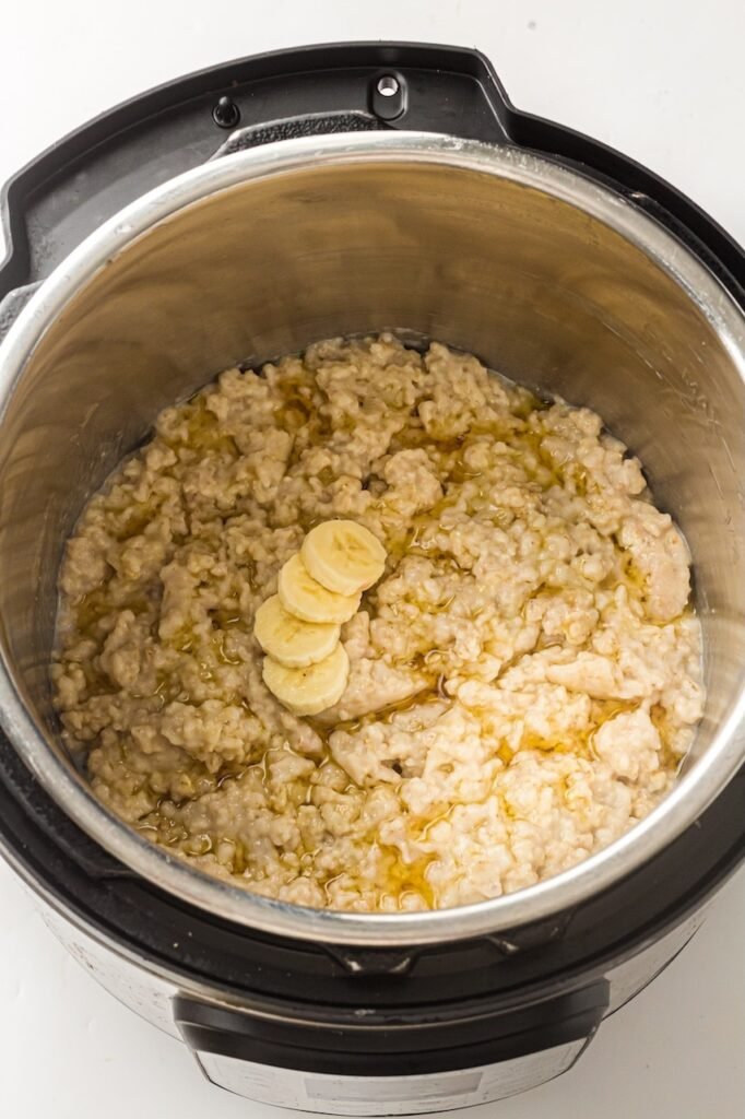 Creamy cooked oatmeal inside topped with sliced banana and a light drizzle of syrup, showing a finished serving ready to eat after pressure cooking.