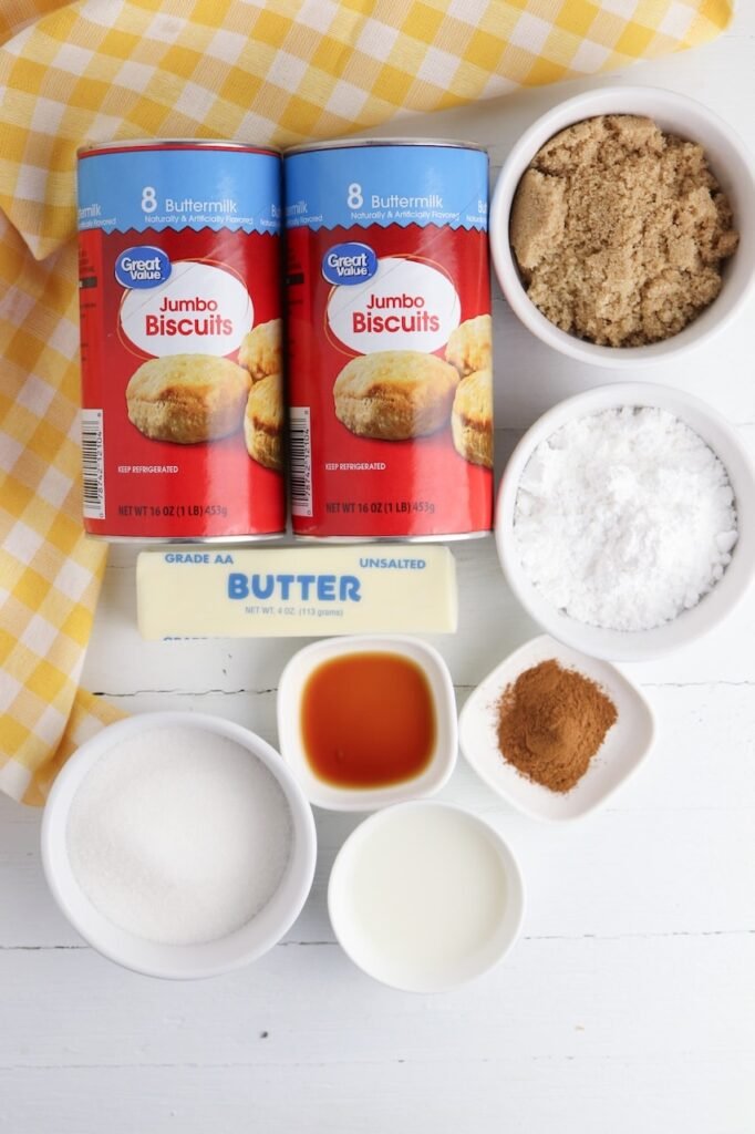 Overhead view of ingredients for pull apart King Cake including canned biscuits, cinnamon, sugar, butter, and vanilla extract.