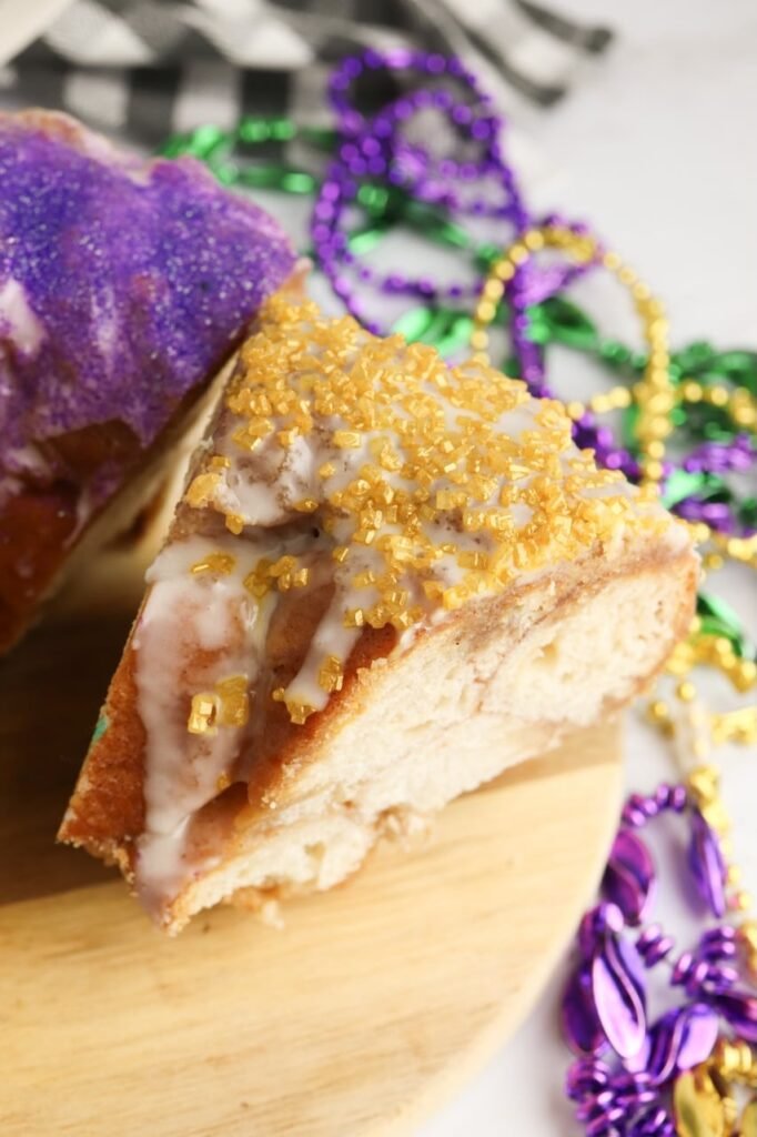 Close-up of sliced Mardi Gras King Cake showing the crumb texture and green and purple sugar glaze on top