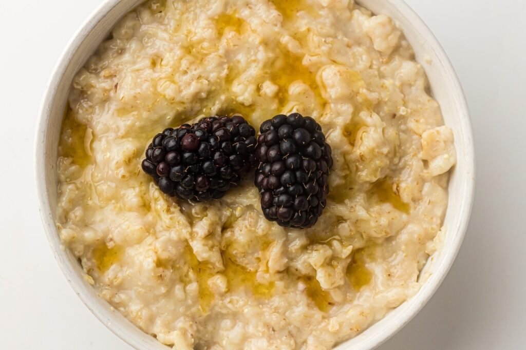A bowl of creamy cooked oatmeal topped with fresh blackberries and a light drizzle, showing a finished serving of Instant Pot oatmeal ready to eat for breakfast.