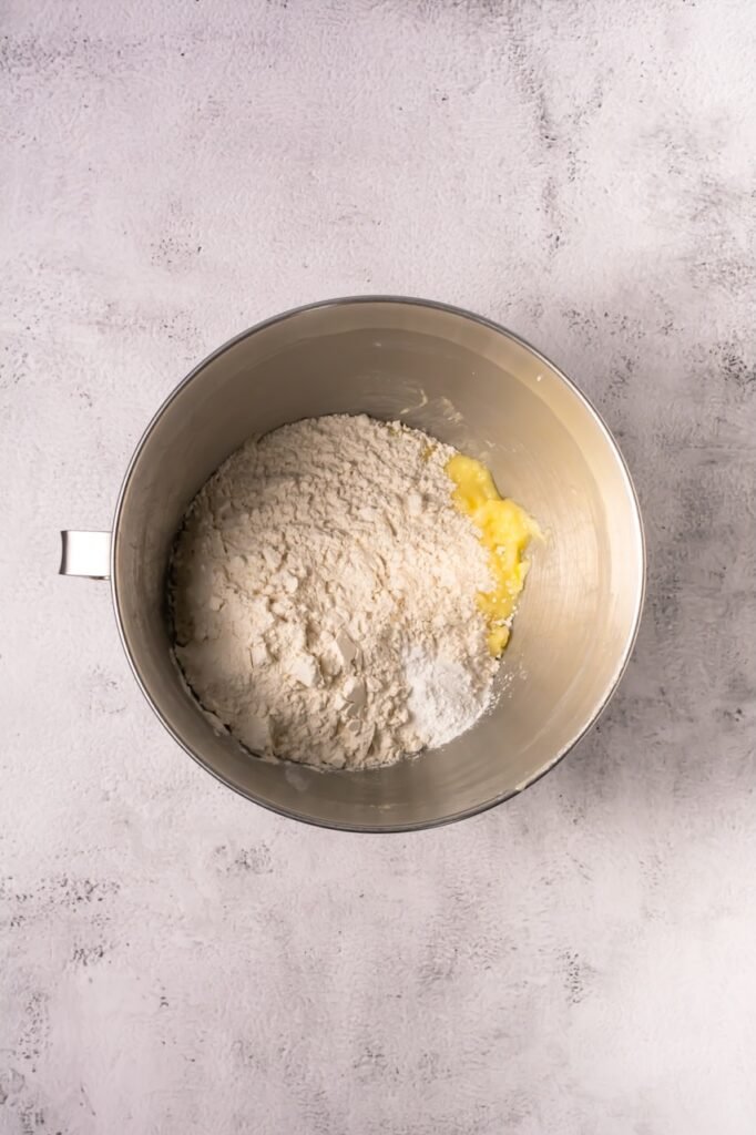 Flour and dry ingredients added to a mixing bowl with butter mixture while preparing.