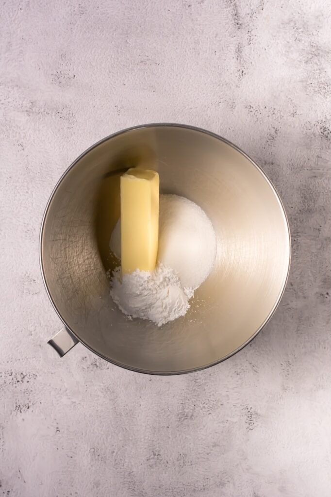 Butter, granulated sugar, and powdered sugar in a stand mixer bowl ready to be creamed together.