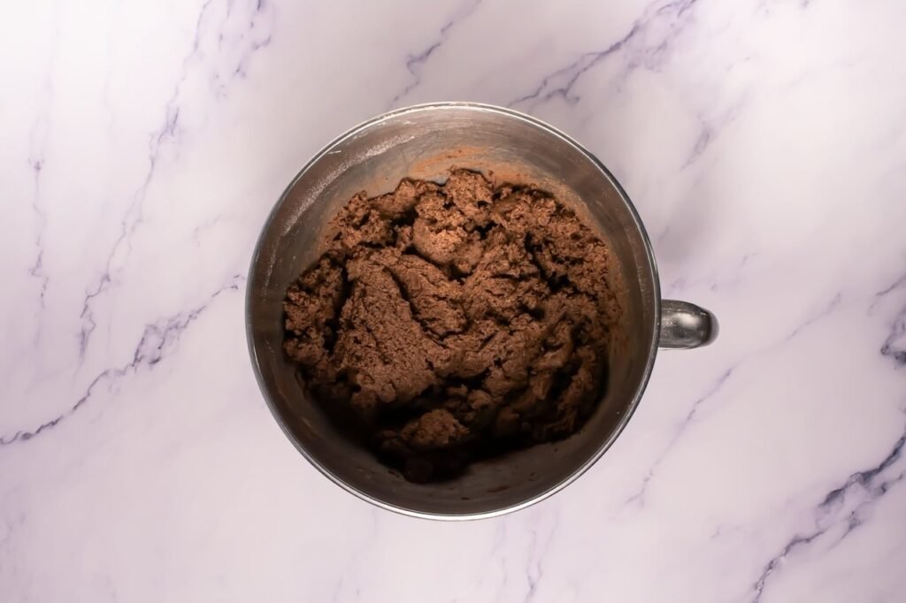 Overhead view of thick chocolate cookie dough fully mixed in a bowl, showing the correct texture for crumbl chocolate Oreo cookies before baking.