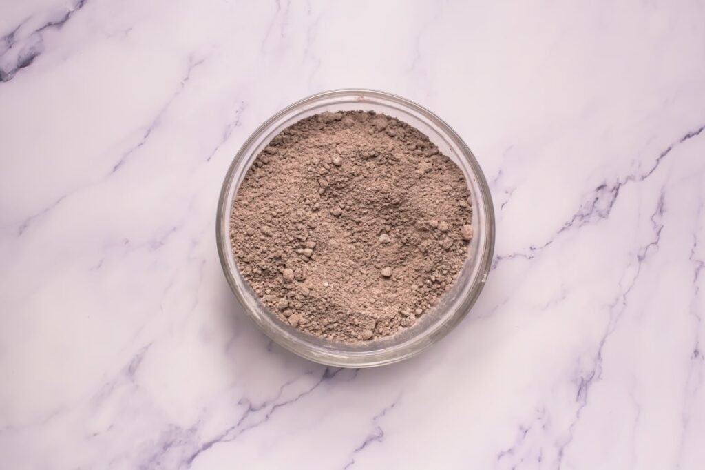 Overhead view of a bowl with evenly mixed dry ingredients, including flour, cocoa powder, and Oreo crumbs, showing the correct texture for crumbl chocolate Oreo cookies.