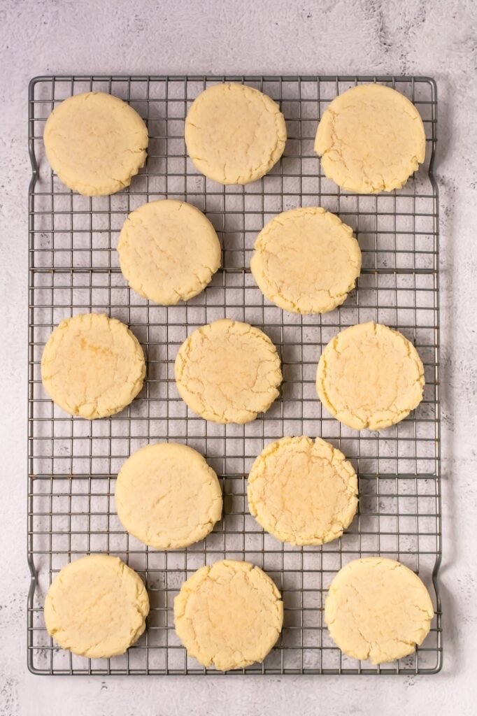 Freshly baked coconut lime cookies cooling on a wire rack after baking before adding lime frosting.