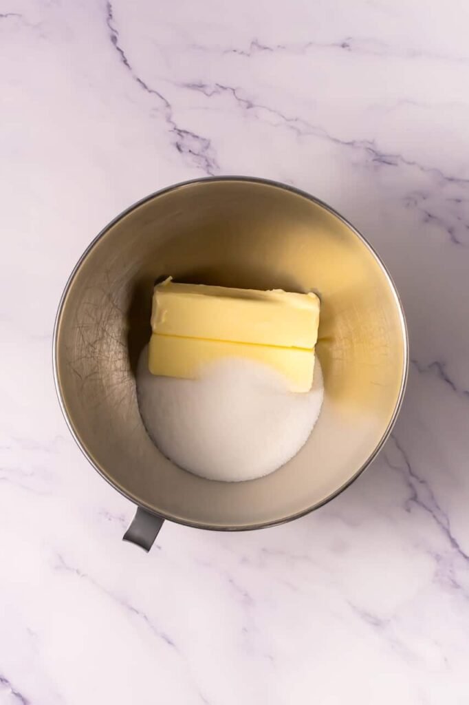 Stand mixer bowl containing softened butter and sugar before creaming together to make cookie dough for cookies and cream milkshake cookies.