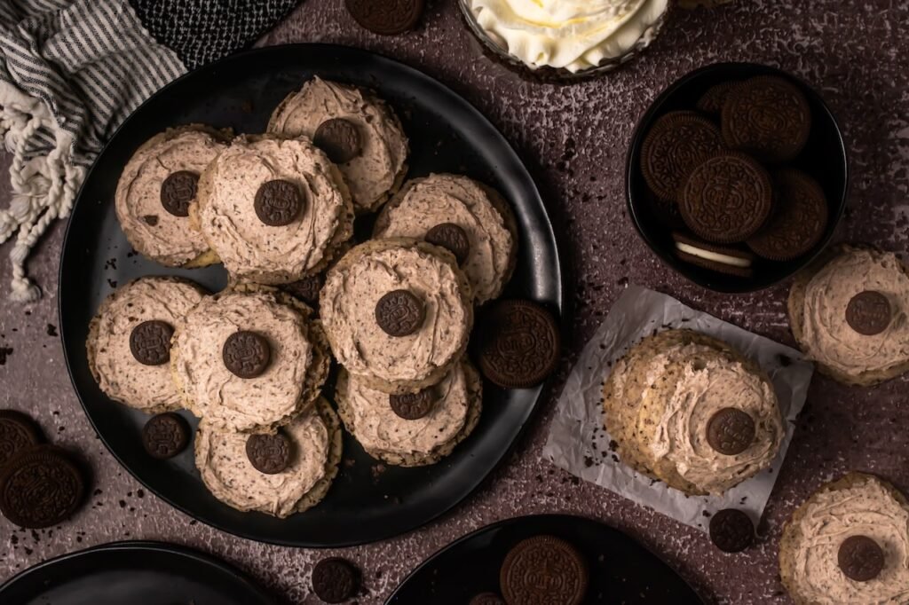 Overhead view of thick cookies cream milkshake cookies topped with Oreo frosting mini Oreo cookies arranged on black serving plate surrounded by Oreo cookies.